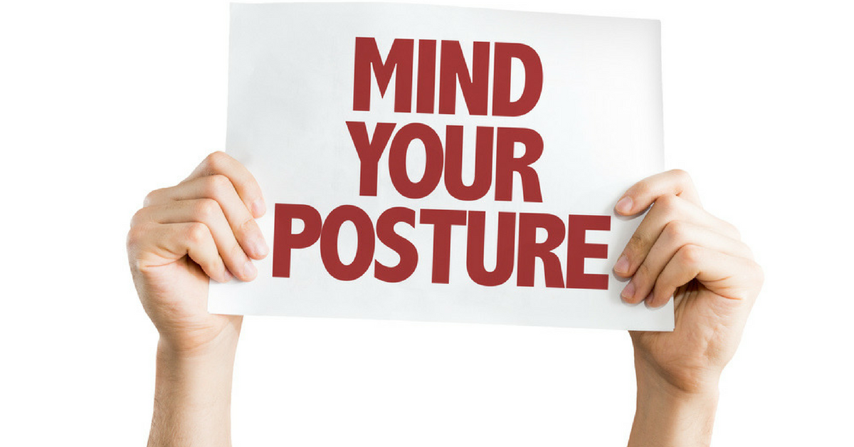 person holding sign that reads Mind Your Posture